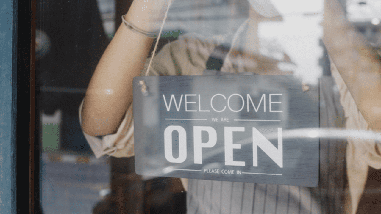 young girl hanging open sign on door